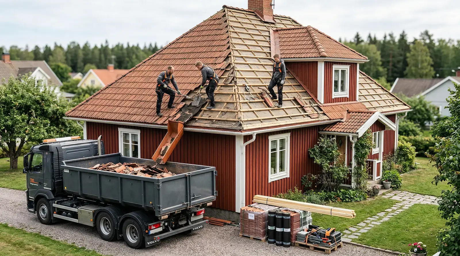 Takläggare renoverar rött trähus med lastbil och material framför.