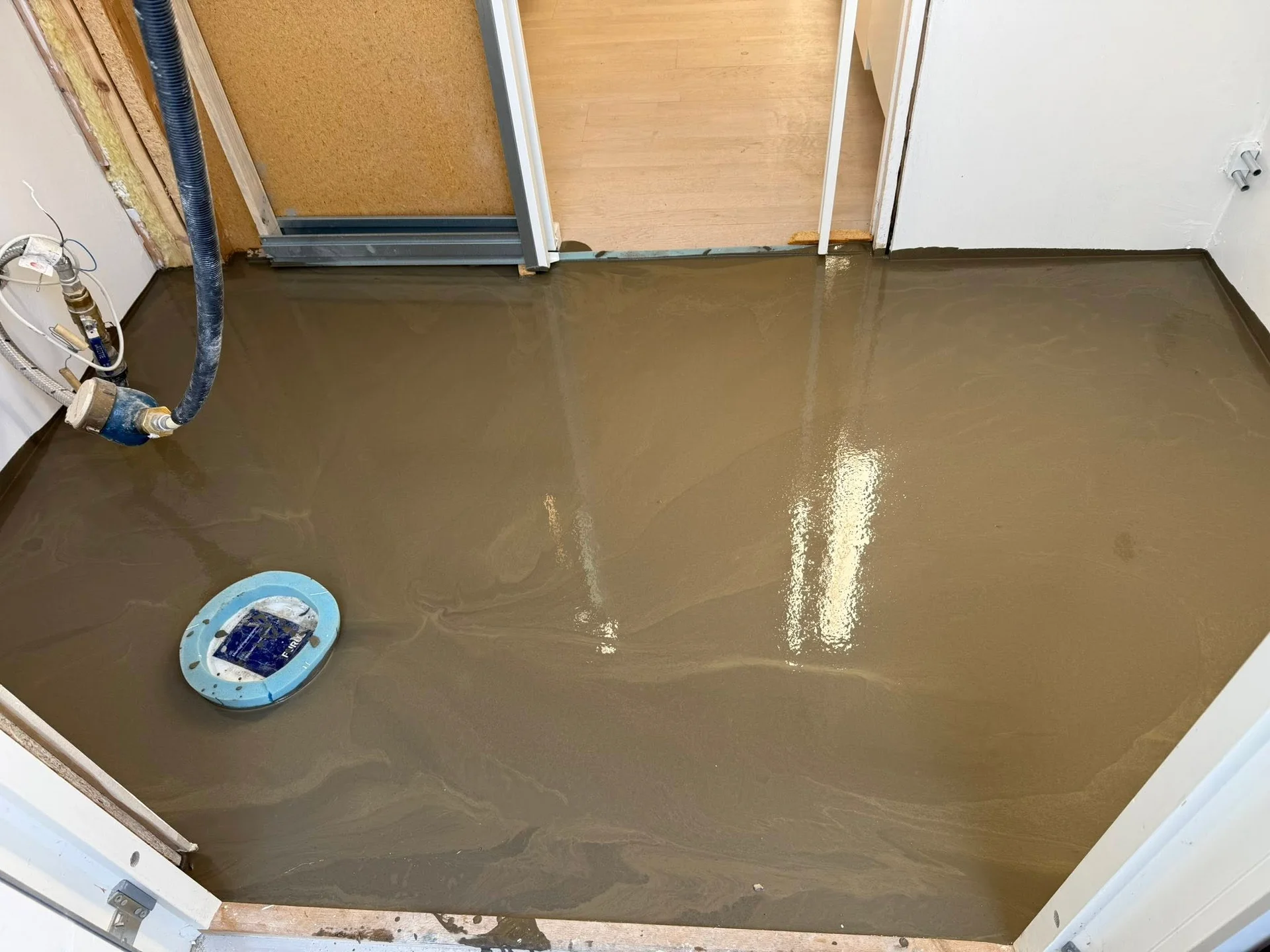 Kvinna lägger kakel på golvet i ett badrum under renovering.